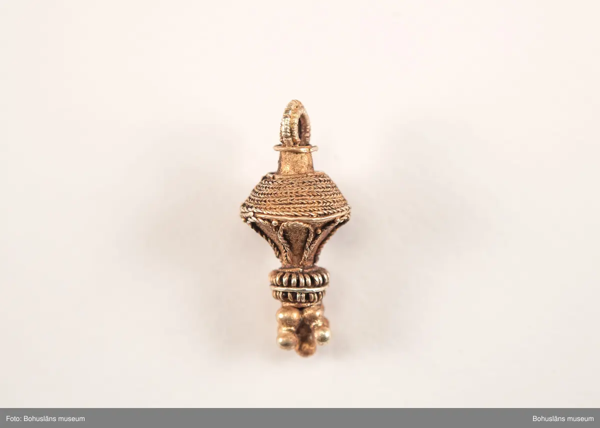 Ett utsökt intakt hängsmycke av guld, en s k päronformad berlock. Överst på hänget, finns en ögla för upphängning på ett band, halskedja eller liknande. Dekoren är utförd i s k filigranteknik, och visar på högt hantverksmässigt kunnande. Mycket tunna, tvinnade eller flätade guldtrådar är lagda ovanpå och runt hängets övre del. På hängets undre del är flera små runda guldkulor (granuleringar) fästade. Berlocken tillhör "typ III", enligt von Müllers typologi (se Müller 1958). Formmässigt har hänget sitt ursprung i östra Medelhavet och området kring Svarta havet.

Denna typ av hängsmycken är mycket ovanligt att hitta i våra trakter, det är endast en handfull som tidigare påträffats i Sverige och de flesta på Öland. Desto fler har däremot hittats i Danmark (se Rapport 2020:166, s.12).

Hänget/berlocken hittades, tillsammans med fyra spännen av brons, ett 40-tal keramikskärvor, brända och obrända ben, däribland en tand, flintavslag och bitar av en dekorerad kam av horn. Graven innehöll två individer. Den ena var jordlagd utan kremering och den andra kremerad. Den jordlagda individen hade endast ett fåtal ben och tänder bevarade. De visade sig tillhöra en ung person, ca 16-20 år gammal. Förmodligen en kvinna, vilket de gravgåvor som var nedlagda i graven visade.
Den andra individen, till vilken de brända benen hörde, var även det en ung person. 
För mer info om, och tolkning av fyndet se rapport Arkeologerna 2020:166.