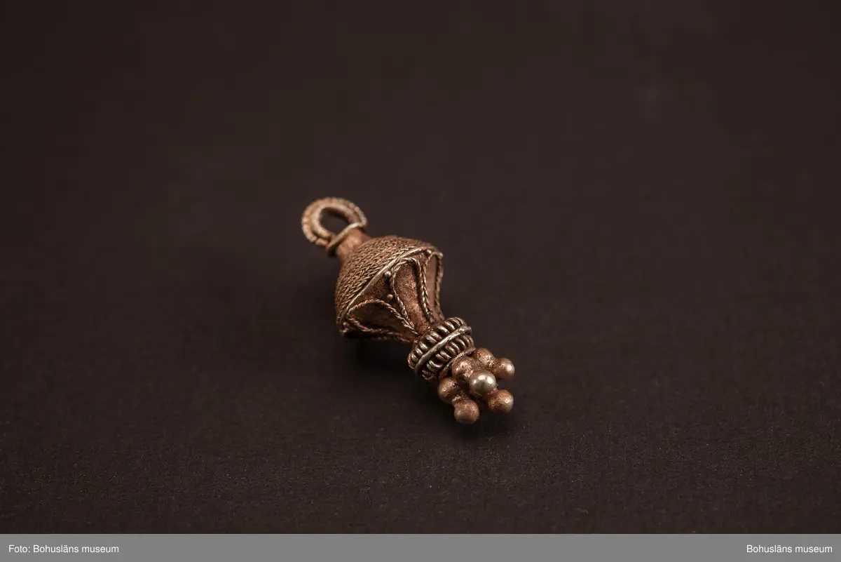 Ett utsökt intakt hängsmycke av guld, en s k päronformad berlock. Överst på hänget, finns en ögla för upphängning på ett band, halskedja eller liknande. Dekoren är utförd i s k filigranteknik, och visar på högt hantverksmässigt kunnande. Mycket tunna, tvinnade eller flätade guldtrådar är lagda ovanpå och runt hängets övre del. På hängets undre del är flera små runda guldkulor (granuleringar) fästade. Berlocken tillhör "typ III", enligt von Müllers typologi (se Müller 1958). Formmässigt har hänget sitt ursprung i östra Medelhavet och området kring Svarta havet.

Denna typ av hängsmycken är mycket ovanligt att hitta i våra trakter, det är endast en handfull som tidigare påträffats i Sverige och de flesta på Öland. Desto fler har däremot hittats i Danmark (se Rapport 2020:166, s.12).

Hänget/berlocken hittades, tillsammans med fyra spännen av brons, ett 40-tal keramikskärvor, brända och obrända ben, däribland en tand, flintavslag och bitar av en dekorerad kam av horn. Graven innehöll två individer. Den ena var jordlagd utan kremering och den andra kremerad. Den jordlagda individen hade endast ett fåtal ben och tänder bevarade. De visade sig tillhöra en ung person, ca 16-20 år gammal. Förmodligen en kvinna, vilket de gravgåvor som var nedlagda i graven visade.
Den andra individen, till vilken de brända benen hörde, var även det en ung person. 
För mer info om, och tolkning av fyndet se rapport Arkeologerna 2020:166.