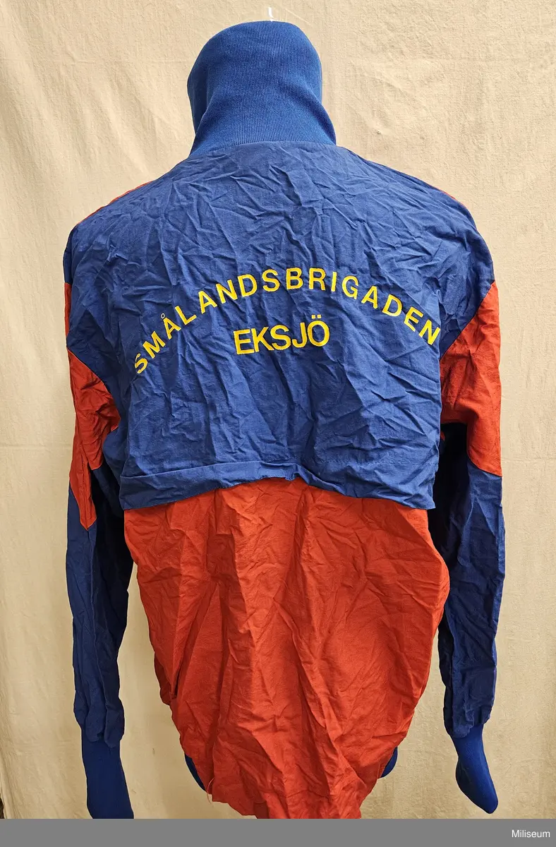 Träningsoverallsjacka med Smålandsbrigadens emblem på bröstet och text Smålandsbrigaden Eksjö på ryggen. Storlek L.