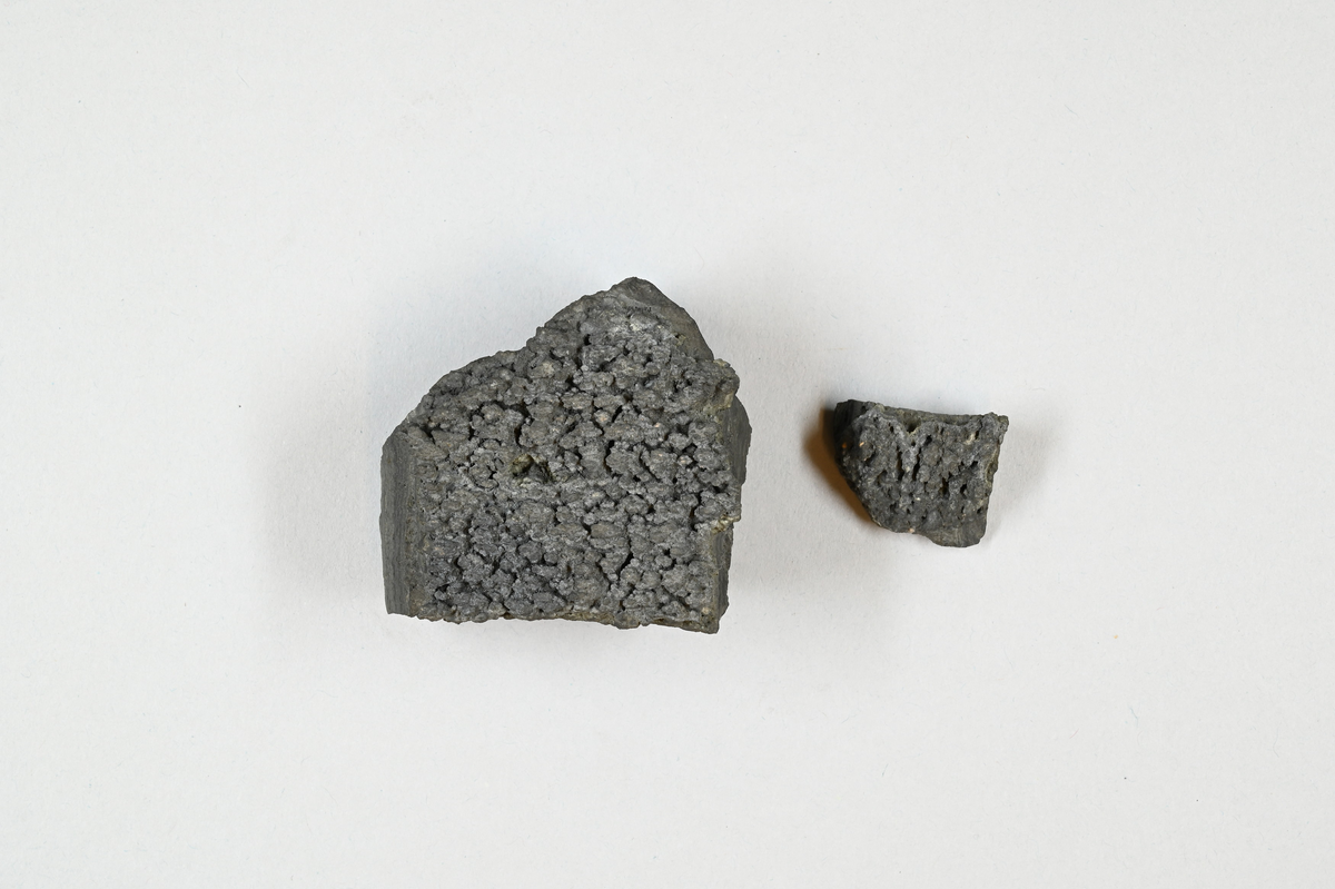 Två mineralprov, grå. Tre tillhörande lappar med information bland annat: "Magnetkis från Ringerike" och: "Ugnsbrott, från Huså, Sebenius".