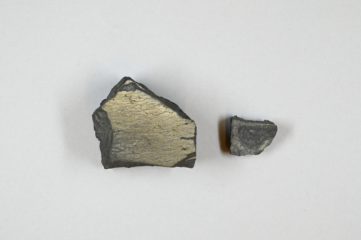 Två mineralprov, grå. Tre tillhörande lappar med information bland annat: "Magnetkis från Ringerike" och: "Ugnsbrott, från Huså, Sebenius".