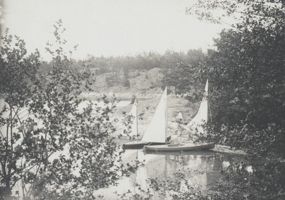 Segelkanoter vid en skärgårdsklippa.