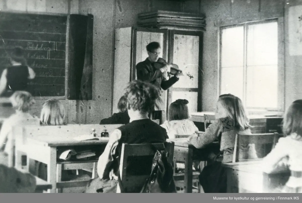 Klasserom på Kamøyvær skole. Lærer Helge Berg spiller fiolin for elevene. Ca. 1948.