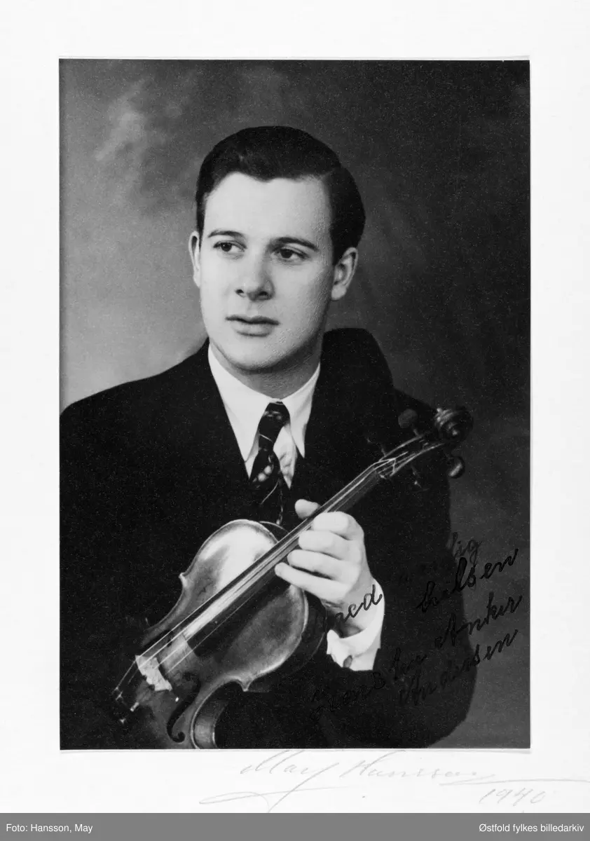 Portrett av Karsten Anker Andersen 1940. Han overtok dirigentplassen i Fredrikstad Musikkforening etter Severin Svensen da han var 20 år gammel. Andersen var solist, konsertmester, dirigent 1940-43.
Dedikasjon: "Med venlig hilsen Karsten Anker Andersen" Autograf.