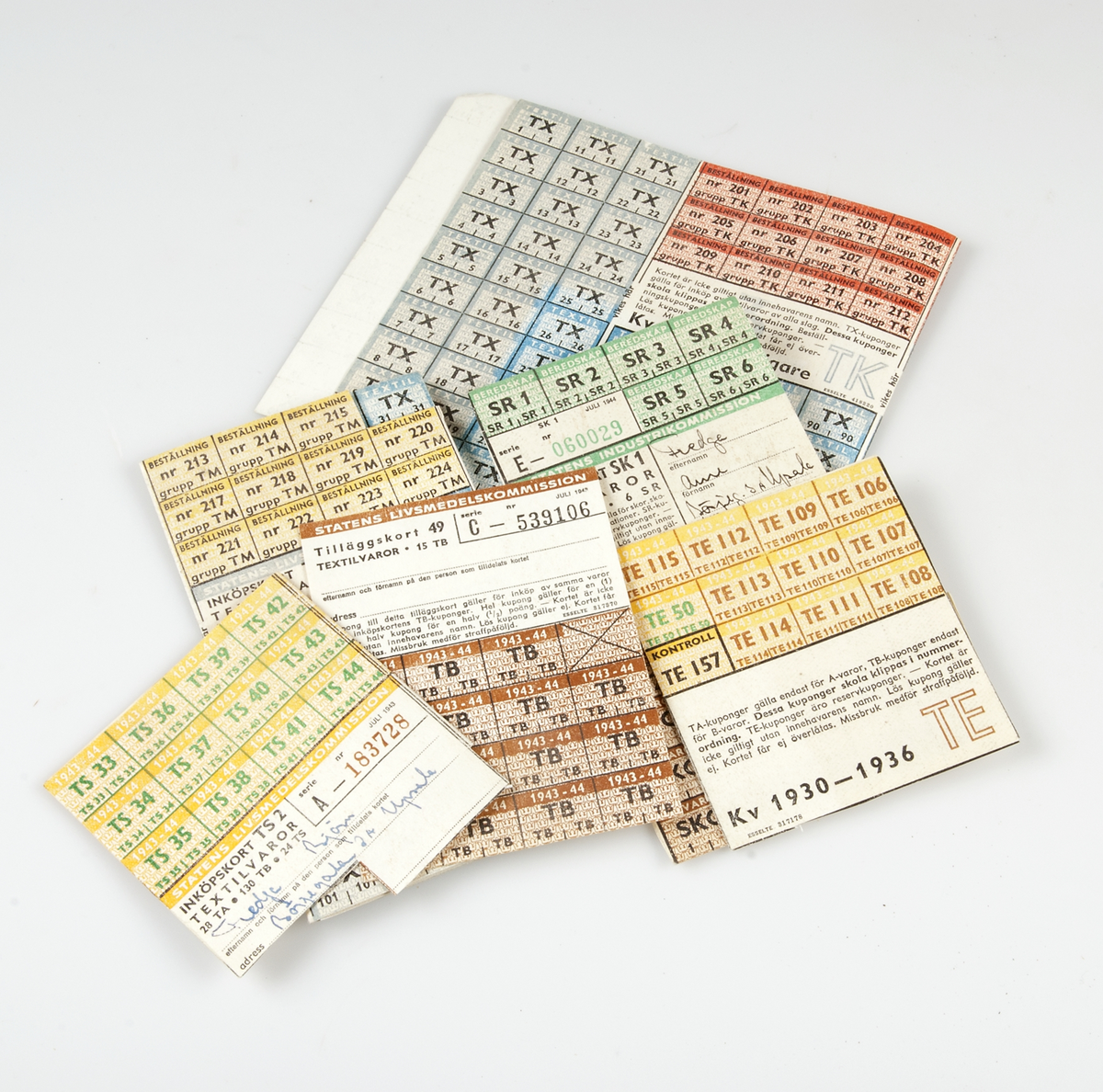 Brunt kuvert Ransoneringskort  för textil och skovaror utgivna av Statens Livsmedelskommission, utställda på olika medlemmar i familjen Fredga, Börjegatan 3 A, Uppsala: Arne, Brita, Karl, Björn, Sven, Märta , Kerstin Fredga. Samt ur tidningen utklippt Ransoneringskalender från 1944, gulnad.