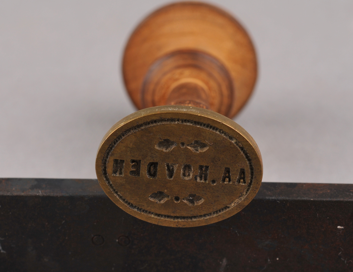 Stempel med dreia treskaft. Stempelet er ovalt. På stemplet står det: AA. HOVDEN.