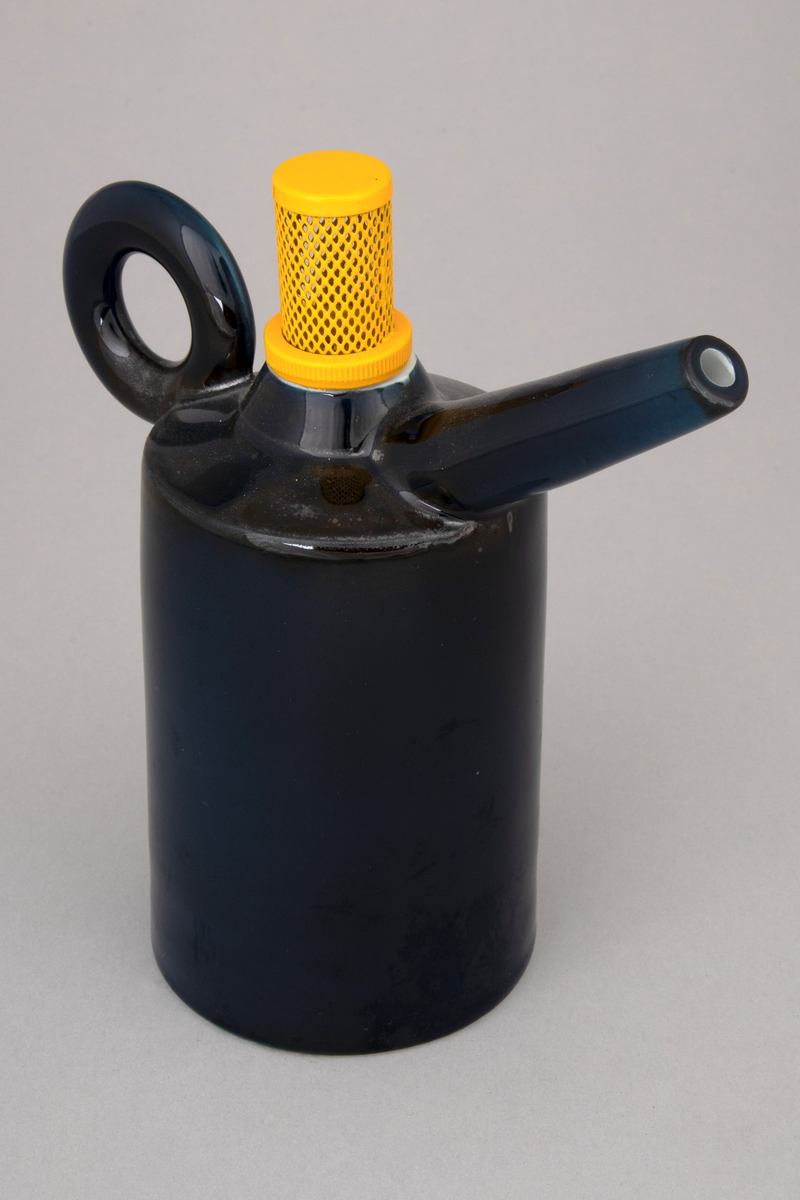 Installasjon med seks polykrome kanner i håndbygd porselen på et rustent bord med glassplate. Kannene er glasert og vedfyrt. Korkene på fem av kannene er lagd av funne komponenter. En har en korkopptrekker, to har industrielle komponenter i lakkert stål og to har gummikomponenter.