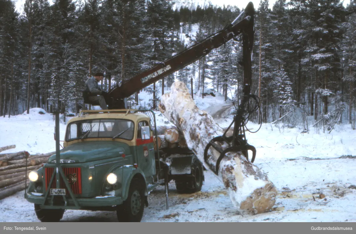 Sjåfør Jakop Moen (f. 1935) lesser ein stor rotstokk på tømmerbilen