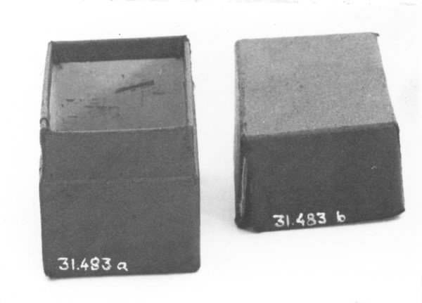 a) Rektangulär ask, överklädd med tyg. Svartmålad.Längd: 8,8 cm, bredd: 4,9 cm, höjd: 4,8 cm.b) Samma som a).Längd: 8,8 cm, bredd: 4,9 cm, höjd: 3,1 cm. 