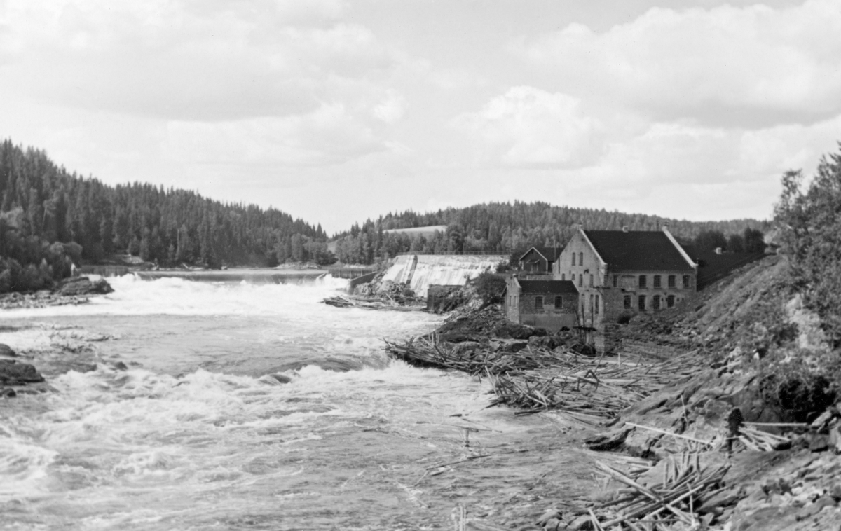 Fra Glomma ved Kykkelsrud i Askim i Østfold. Fotografiet er tatt i motstrøms retning, med en overløpsdam til venstre, en kraftverksdam til høyre for sentrum og en fabrikkbygning til høyre. Fabrikken er det nedlagte A/S Glommens Træsliberi. Tresliperiet ble etablert av grunneieren Anders C. Furuholmen i kompaniskap med skipsreder Johan Smith og salmaker Johan Arnt Martinius Lilloe i 1886, med vannkraft fra fossen som energikilde. Eierne forsto at det var mer å tjene på elektrisiteten enn på tremassen, og i slutten av 1890-åra forsøkte de å reise midler til et stort kraftverk. Det endte med konkurs, og det tyske selskapet Schuckert & Co. overtok virksomheten i ly av sin eierandel i A/S Hafslund i Sarpsborg, som kunne innvie kraftstasjonen i 1903. Tresliperiet ble utleid til selskapet A/S Lilloe & Smith, som holdt det gående til 1926. Deretter fortsatte morselskapet Hafslund tremasseproduksjonen fram til 1929. Her var virksomheten med andre ord nedlagt da dette fotografiet ble tatt. Kraftstasjonen ble utvidet og modernisert i 1939-1941.