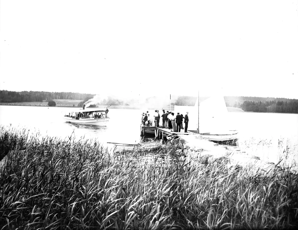 Båten "Brunnsviken" anländer till bryggan vid Sätra äng i Danderyd den 9 juli 1899.
Bilden är troligen tagen av Axel Pehrson.
Glasplåten låg i ett kuvert som hade bildtexten:
"Båten kommer, den 9 juli 1899."