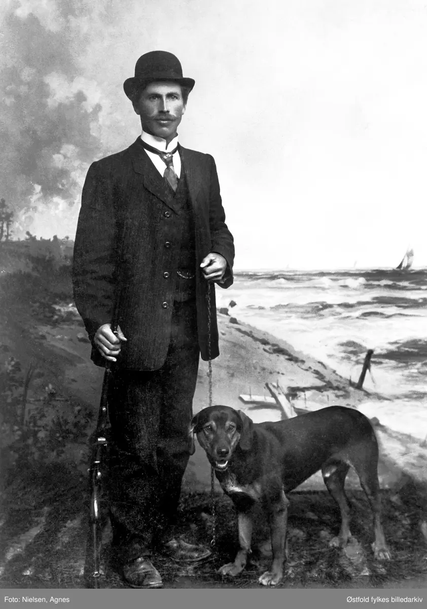 Portret av Erik Lunde fra Varteig  med schweizerstøveren Rapp, ukjent år. Fotobakgrunn av et kystlandskap. Visittkort.