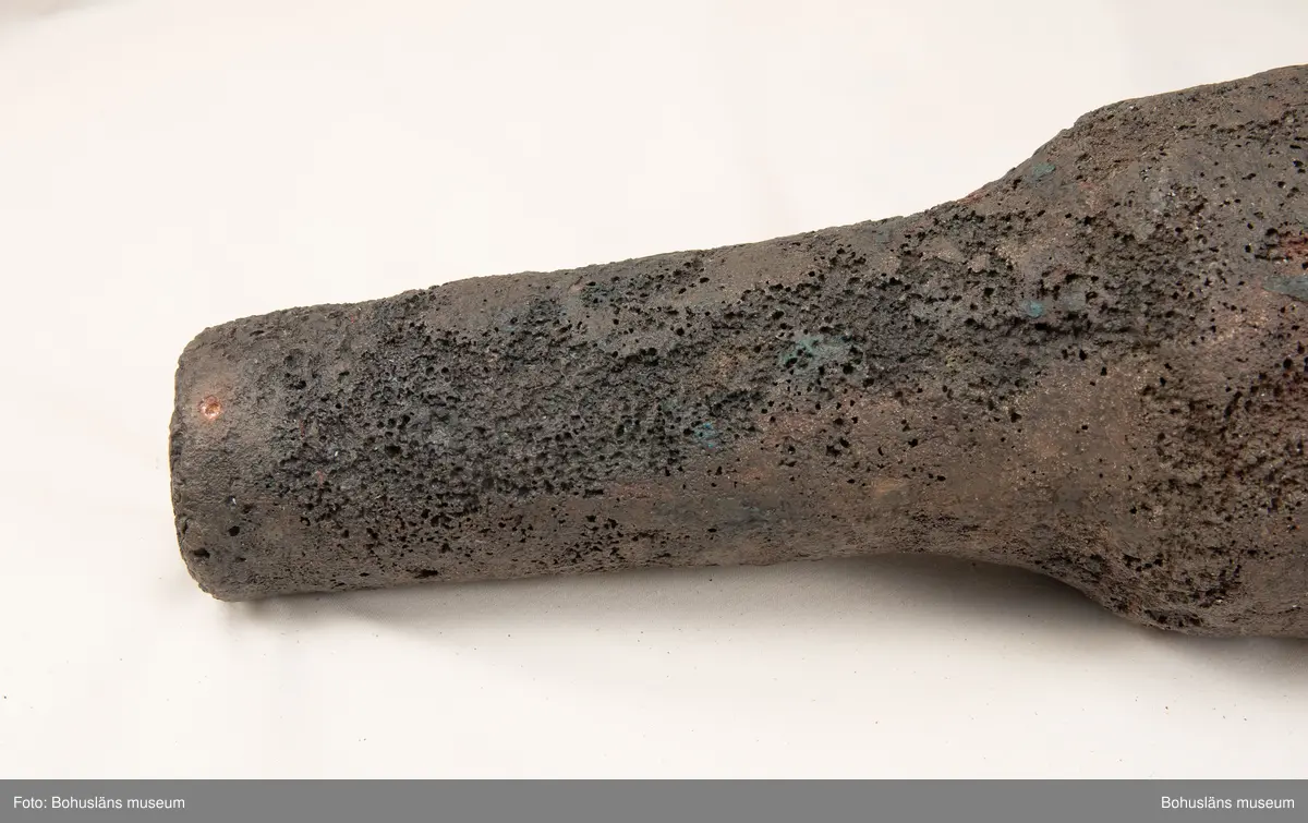 Medeltida bronskanon, s k bombard, gjuten i kraftigt gods. 
Ett sjöfynd upphittat av amatördykare i Marstrandsfjorden. Kanonen kan dateras till 1300-1400-tal. 
Dessa tidiga eldrör göts vanligtvis i brons, d .v.s. en legering av koppar och tenn. Legeringars sammansättning kan dock variera mycket och tidiga exempel finns där, som i detta fallet, tenn bytts ut mot bly och zink. 
Kanonen är 47,5 cm lång, mynningens diameter är 19 cm och den väger ca 18,7 kg. Fänghålet är synligt och har en nuvarande diameter på ca. 1 cm. Rester av en laddning i form av fastkorroderad textil sitter kvar längst in i kanonens rör. Materialet består antingen av hampa eller lintyg. En C14-analys av tyget daterar kanonen till 1300-tal. Krutets sammansättning har inte gått att fastställa.

Artikel ur Populär Arkeologi 2010: "Bombarden från Marstrand" - Vid dykning vid grundet Hannehakarna, väster om Marstrand, fann en sportdykare för några år sedan en märklig tingest, som visade sig vara en liten trattformig bronskanon, 47,5 cm lång och med en mynningsdiameter av 19 cm. Liknande mynningsladdade kanoner, eller bombarder som de kallades, finns bevarade på flera håll runt om i Europa. Vanligen är de dock tillverkade av järn och inte brons. Dateringarna är som regel mycket osäkra, men majoriteten av fynden tycks härröra från 1300- eller 1400-talet.

Fyndplatsen, i anslutning till ett farligt undervattensgrund, talar för att kanonen härrör från en fartygsförlisning. När den påträffades fanns fortfarande en del av laddningen kvar. En kol 14-analys av textilmaterial från laddningen daterar fyndet till 1300-talet.

Marstrandsbombarden utgör därmed ett av de äldsta arkeologiska beläggen för skeppsartilleri i Nordeuropa. Dåtidens artilleriammunition bestod av runda, handknackade kanonkulor av sten. Sådana stenkulor har bland annat bärgats från Skanörskoggen från omkring år 1390. Någon samtida skeppskanon har däremot inte tidigare påträffats."