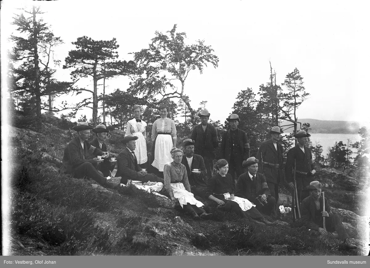 Gruppbild från en hemvärnsövning i Juniskär. Män i landsstormsuniform och vapen samt kvinnor i serveringskläder, det bjöds på kaffe och bullar.