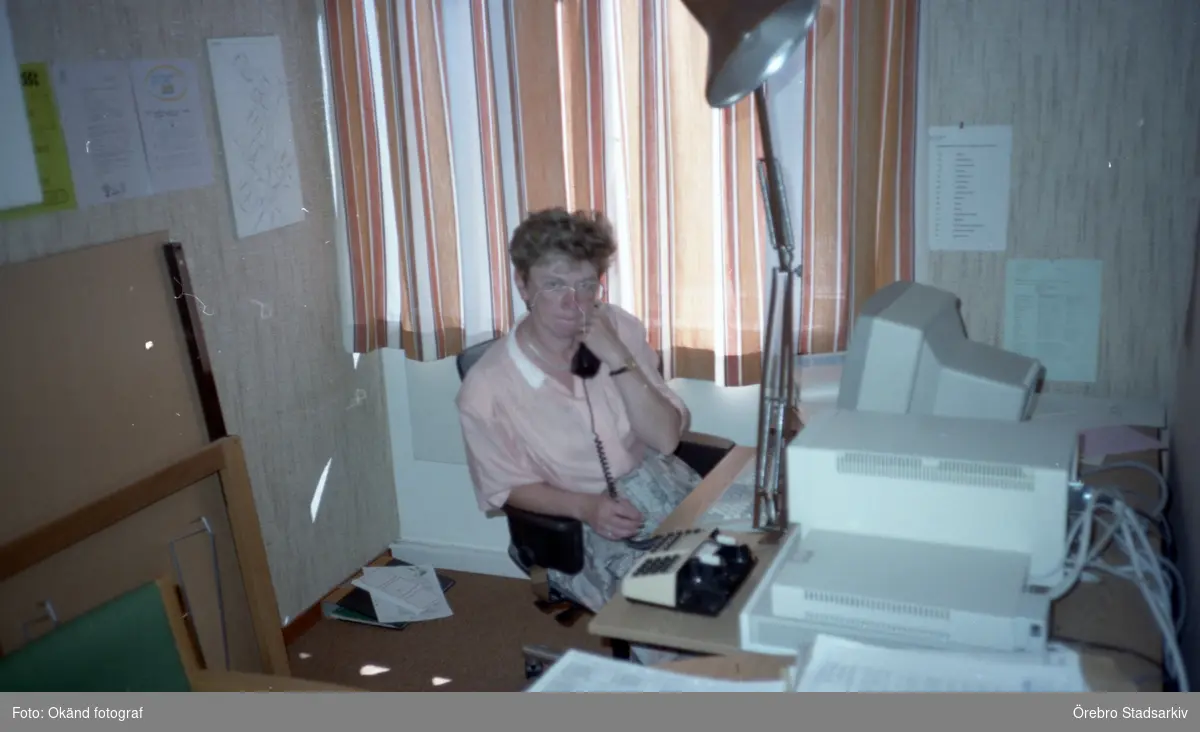 Kvinna i telefon vid skrivbord