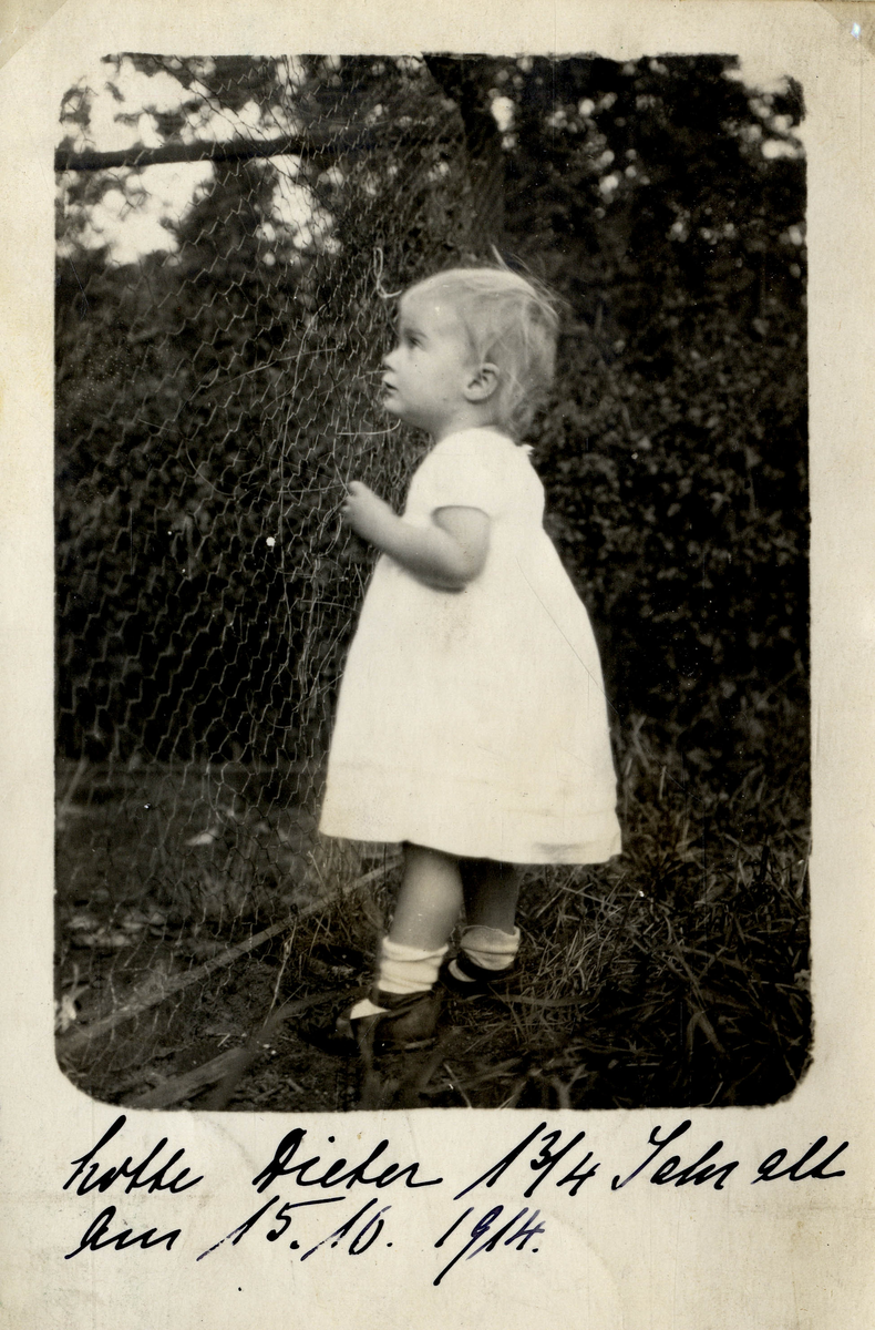 Utendørs fotografi av liten jente ved nettinggjerde.
