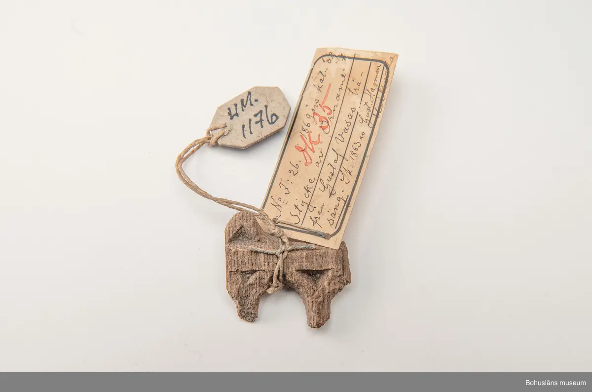 Fragment av större träföremål i ek, ornamenterad på framsidan i plattskärningsteknik. 
Enligt påskrift på äldre, vidhängande föremålsetikett: "Stycke av Ornament från Gustaf Vasas träsäng."
Ur handskriven katalog över Uddevalla Musei Historiska Samlingar, svenska avdelningen, yngre föremål upprättad  år 1916 av Knut Adrian Andersson, intendent från 1 oktober 1915:
"No 56 = (F:26 i 1869 års katalog av G. Brusewitz)
Stycke av trä-ornament från
Gustaf Wasas säng. Skänkt 1863 av Gustaf
Hagman i Uddevalla".

Ur handskrivna katalogen 1957-1958:
Stycke av träornamenet
Mått: 3,7 x 3,4 x 0,7 cm; (skall vara fr. Gustav Vasas säng).

Litt.: Utställningskatalog "Ärva och Förvärva Vårda eller Fördärva?", Stiftelsen Läckö institutet, 1995.
Utställningskatalog "Guide till svenska folkets kungaminnen", Livrustkammaren 2003.