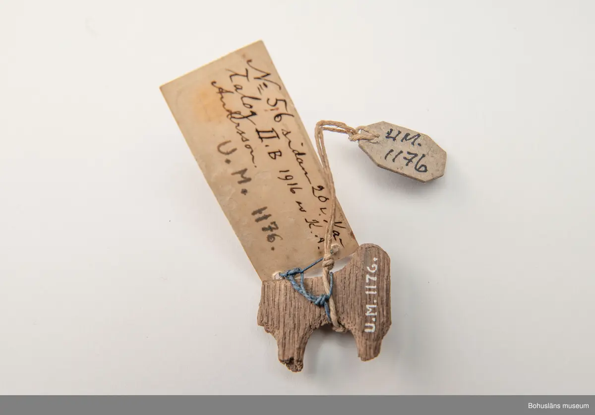 Fragment av större träföremål i ek, ornamenterad på framsidan i plattskärningsteknik. 
Enligt påskrift på äldre, vidhängande föremålsetikett: "Stycke av Ornament från Gustaf Vasas träsäng."
Ur handskriven katalog över Uddevalla Musei Historiska Samlingar, svenska avdelningen, yngre föremål upprättad  år 1916 av Knut Adrian Andersson, intendent från 1 oktober 1915:
"No 56 = (F:26 i 1869 års katalog av G. Brusewitz)
Stycke av trä-ornament från
Gustaf Wasas säng. Skänkt 1863 av Gustaf
Hagman i Uddevalla".

Ur handskrivna katalogen 1957-1958:
Stycke av träornamenet
Mått: 3,7 x 3,4 x 0,7 cm; (skall vara fr. Gustav Vasas säng).

Litt.: Utställningskatalog "Ärva och Förvärva Vårda eller Fördärva?", Stiftelsen Läckö institutet, 1995.
Utställningskatalog "Guide till svenska folkets kungaminnen", Livrustkammaren 2003.