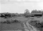 Torpet Storängen när sommaren stod för dörren 1922. Hemman under Bjärka Säby och beläget på godsets stora ängsområde söder om slotten, därav torpets namn. Storängen finns upptagen i socknens äldsta förtecknade husförhör från 1792 men är sannolikt ännu något äldre. Den som kopplar platsen närmare fototiden finner torparparet Anders Fredrik och Brita Sofia Andersson på platsen från år 1881. Med en barnaskara endast välsignad med döttrar kom här en räcka drängar ha tjänst, som brukligt i korta perioder. Efter nära 40 år på torpet avled Anders Fredrik och en ny ordning i Storängen blev nödvändig. Den fanns i Karl Erik Bovin som sedan 1911 varit gift med det äldre torparparets dotter Ester Johanna. Tillsammans hade de fem barn, varav tre söner, och med dem upphörde behovet av drängar. Istället tycks torpets extra utrymmen erbjudits personal med tjänst närmare huvudgårdens behov. Den gamla torparänkan Brita Sofia bodde kvar till sin död 1929, möjligtvis i undantagsstugan som skymtar till vänster om torpet. Som en sista upplysning kan berättas att Ester Johanna var avliden vid fototillfället. Barnsängsfeber hade tillstött efter nedkomsten av makarnas sistfödda i september 1920.