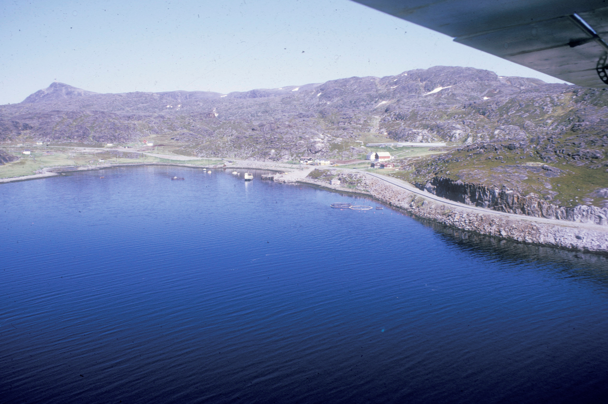 Flyfoto : Kystlandskap, et par merder flyter midt i bildet.