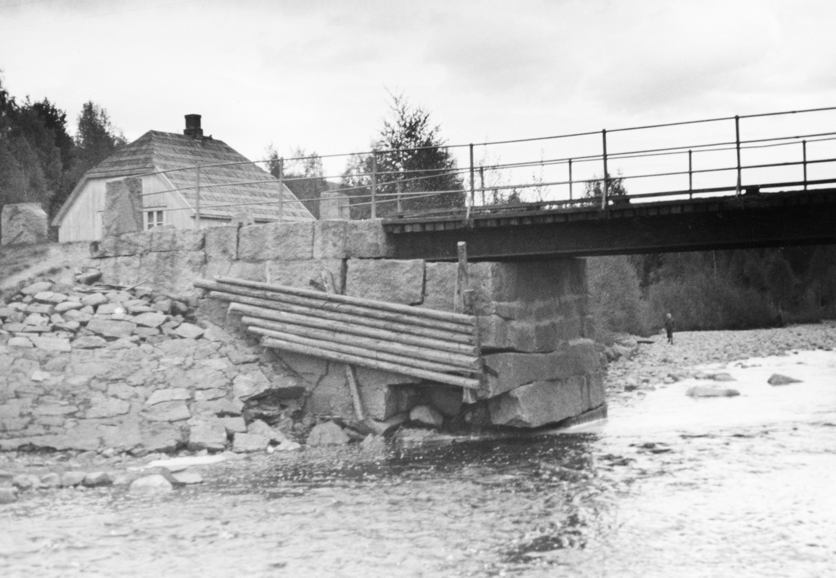 Knapper bru over elva Juråa i Nord-Odal i Hedmark. Dette fotografiet ble tatt i 1936, antakelig for å dokumentere en skade på brukaret på østre elvebredd. Det var murt av kvadret naturstein, men et par av steinene nederst i murverket, på hjørnet på motstrøms side, hadde rast ut. Sida av brukaret var forblendet med en lem, lagd av granne rundstokker, antakelig montert for å avvise fløtingstømmer som kunne legge seg mot brukaret i fløtingssesongen, da vannføringa i Jura brukte å være langt større enn den var da dette fotografiet ble tatt. Elveskråningen ved sida av brukaret var plastret med steinheller, som skulle forebygge erosjonsskader. Knapper bru var ei bjelkebru, med H-bjelker av jern som bar en vegbane av tre. Langs kjørebanens ytterkanter var det montert et rekkverk av jernrør. I bakgrunnen skimter vi et bolighus med halvvalmtak.