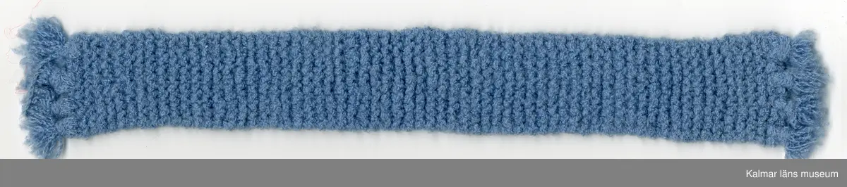 KLM 45519:16:8. Dockhalsduk, långhalsduk, blå, av konstmaterial, handstickad, med frans.