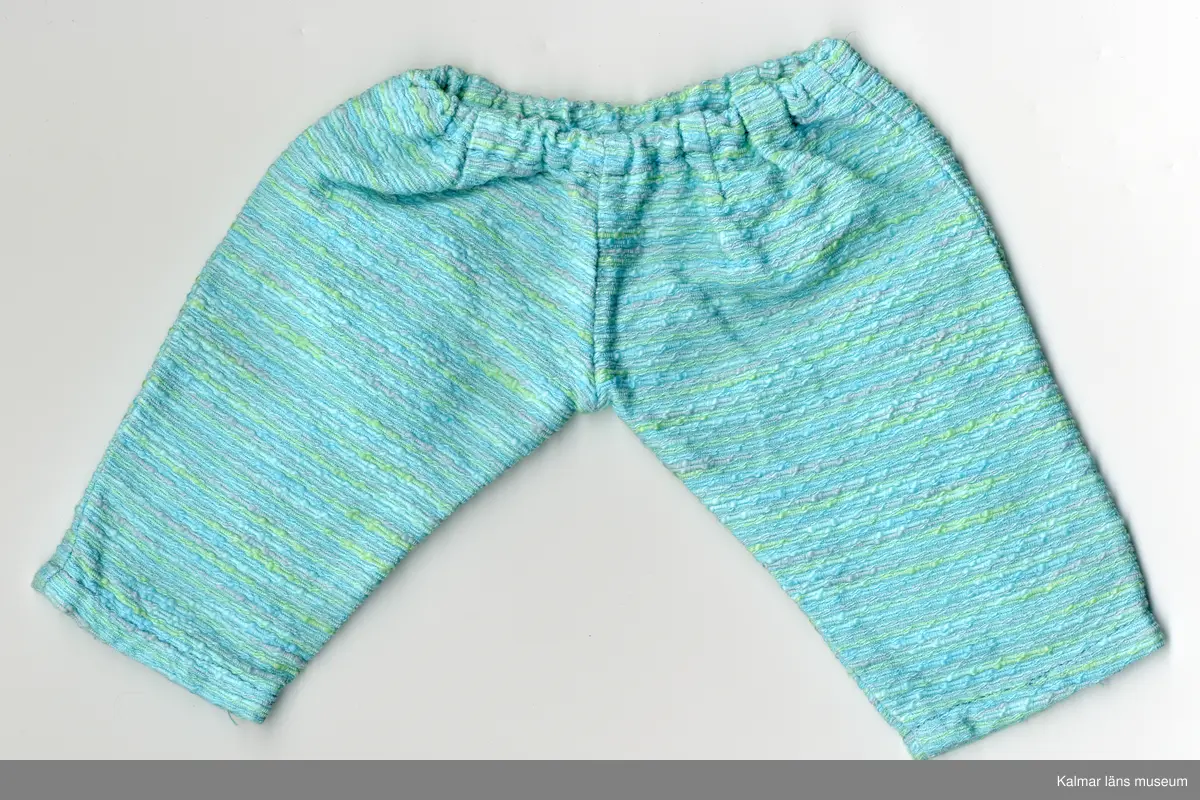 KLM 45519:17:7:1-2. Dockdräkt, byxdress, :1 dockjacka och : 2 dockbyxor, båda plaggen av textil, bomull, turkos, med inslag av gröna och gråa ränder. :1 Jacka, rak modell, kantband, bomull, orangefärgat, kantar halslinning och öppning framtill. :2 Byxa,  resår i midja, långa ben, avsmalnande neråt.