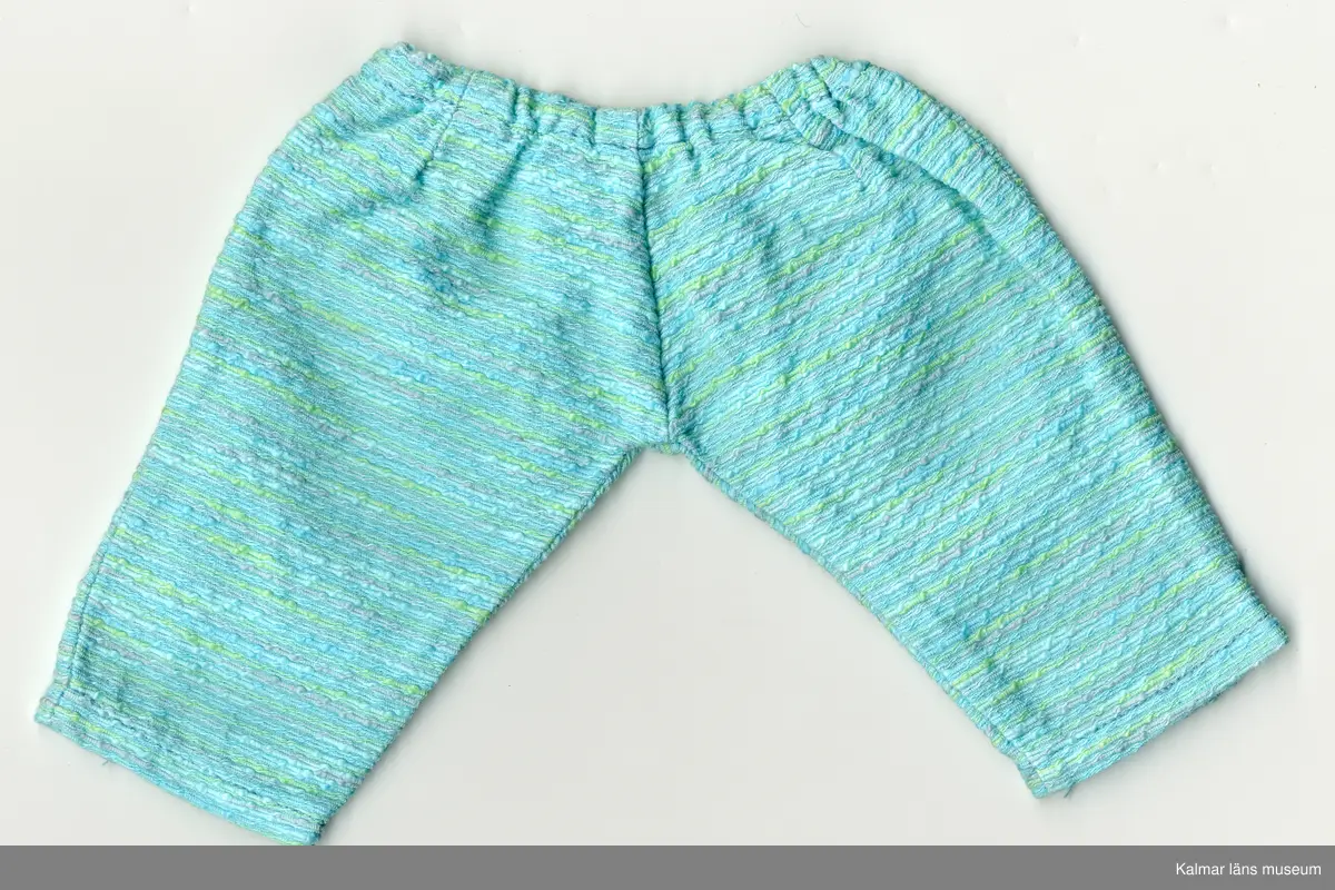 KLM 45519:17:7:1-2. Dockdräkt, byxdress, :1 dockjacka och : 2 dockbyxor, båda plaggen av textil, bomull, turkos, med inslag av gröna och gråa ränder. :1 Jacka, rak modell, kantband, bomull, orangefärgat, kantar halslinning och öppning framtill. :2 Byxa,  resår i midja, långa ben, avsmalnande neråt.
