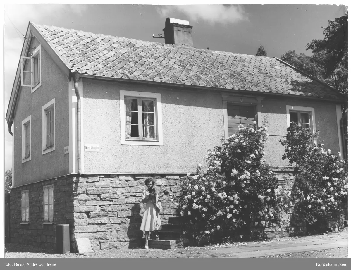 Borgholms äldsta hus på Norra Långgatan, Öland . En kvinna med vad som ser ut att vara en hund i famnen framför huset.