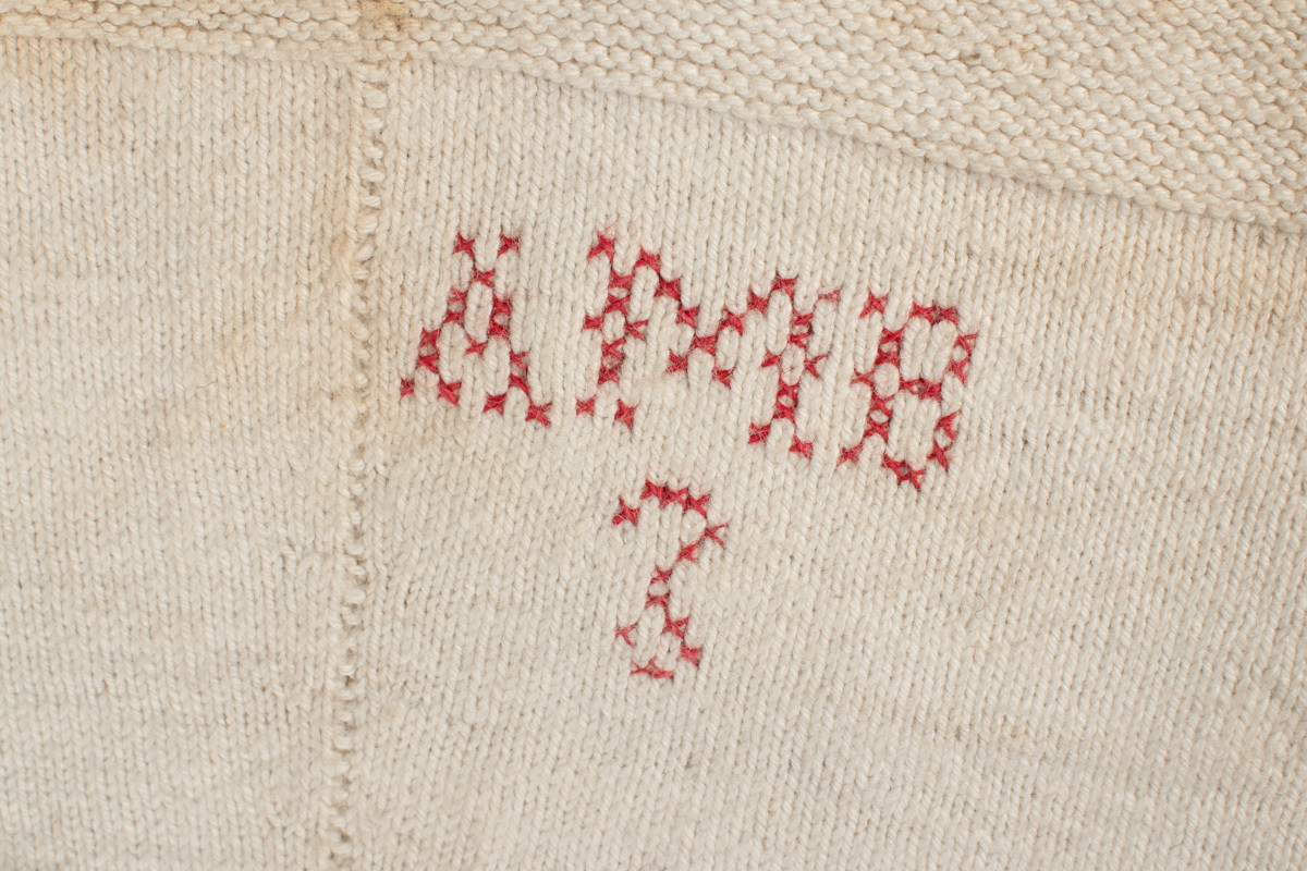 Et par hvite halvstrømper eller knestrømper i glattstrikket bomull med monogrammet AMB brodert i korsting øverst på hver strømpe