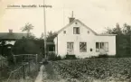 Axel Sparrs speceriaffär i bostadsområdet Lindhem omkring 1915. Fotografen hade för bilden ställt sig på vad som kom att bli Duvgatan och vänt sig mot affären utmed Blomgatan, där affären bar gatunummer 8, vilket idag motsvarar Vretagatan 1 A. Huset i bakgrunden hade adress Blomgatan 10.