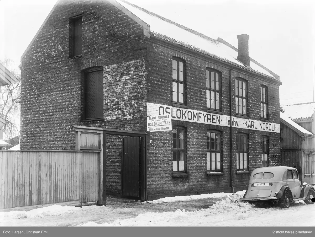 Fabrikkbygningen til Oslokomfyren i Oscar Pedersens vei 9 (tidigere Framsgate 9) i Sarpsborg 1936. 
Malt på vegg og skilt:  OSLOKOMFYREN Innehv. Karl Nordli, fabrik for Oslokomfyren, elektroverksted. 
Bil med kjennetegn A-11719. Bilen er en Renault Monaquatre 1935-36-modell. 

Da fabrikken ble etablert ca. 1926 var det med navnet Kristianiakomfyren, seinere Oslo-komfyren. Hadde først lokaler i Pellygata, flyttet deretter til Fram gate 9  ca. 1934.