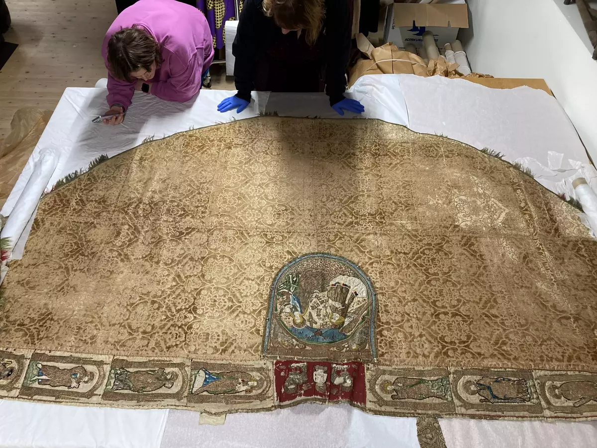 Korkåpa av skuren brungul sammet (ursprungligen röd) med granatäpplemönster och broderier. Kåpan är daterad till Sturegotiken och är troligen ett Vadstena-arbete.

Längs kåpans ytterkant ett band i rött, blått och guld, kantat av silkesfrans randad i flera partier i ursprungligen rött och grönt - nu gulgrått. Utmed framkanterna linnebårder med figurer i aediculor, guld, silver och mångfärgat silke. Å högra sidan jungfru Maria, Petrus, Johannes Döparen, helgon med stav och helgon med kors. Å vänstra sidan okända helgon, Sankt Paulus, Sankt Andreas och okänd apostel med spjut. Figurerna inom rundbågar av guld, på marken strödda blommor.

Vid nacken på rött ylle (ursprungligen täckt av rött taftliknande siden) syns Kristus som smärtoman i halvfigur omgiven av två Guds lamm, på dipens Marie bebådelse med inskrift "AVE MARIA GRA". På broderierna strödda metallpajletter.

Tyget är troligen vävt i Italien under 1400-talets andra hälft. Kåpans montering med band och silverfrans är ursprunglig och kan dateras till 1400-talets senare del eller omkring 1500. Broderierna är troligen utförda i Tyskland under 1400-talets andra hälft. Brämets broderi delvis ibroderat, troligen under 1600- eller 1700-talen.