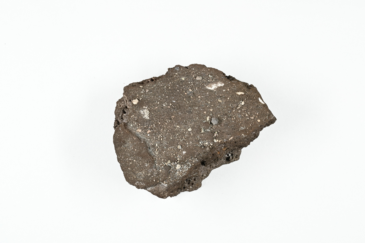 Slaggprov, svart med inslag av koppar. Tillhörande lapp med notering: "Slagg från råkoppar smältning i Kafveltorp, 1902, J. Petrén.".