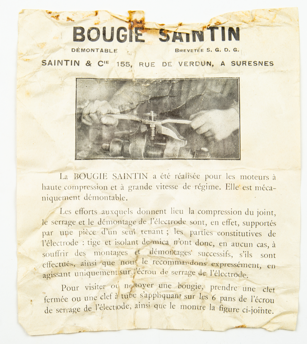 Tändstift, av fabrikat Saintin. Förvaras i originalförpackning i form av ett blått papprör med etikett med bland annat texten Bougies Saintin och dateringen 1927 Juli. I förpackningen följer en dokument. (Tändstift för motorer med hög kompression och hög hastighet.)