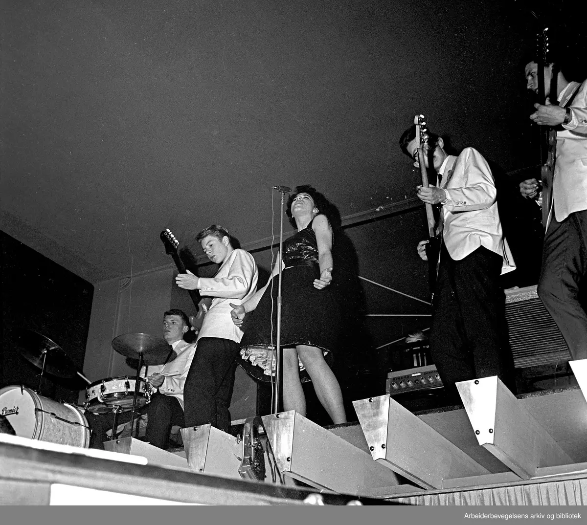 The Vanguards akkompagnerer ukjent deltaker under Arbeiderbladets amatørkonkurranse på Rondo, 19. februar 1963. Fra venstre Hans Helander, Terje Rypdal, Åshild Mathisen (vokalist), Johnny Sareussen og Knut Mikalsen.