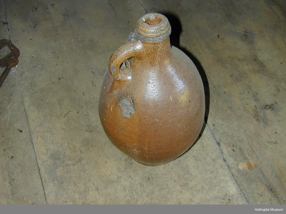 Sirkulært tverrsnitt, kvelva sider, skrår fyrst utover og deretter kraftig innover mot halsopning. Hank øvst ved halsen.