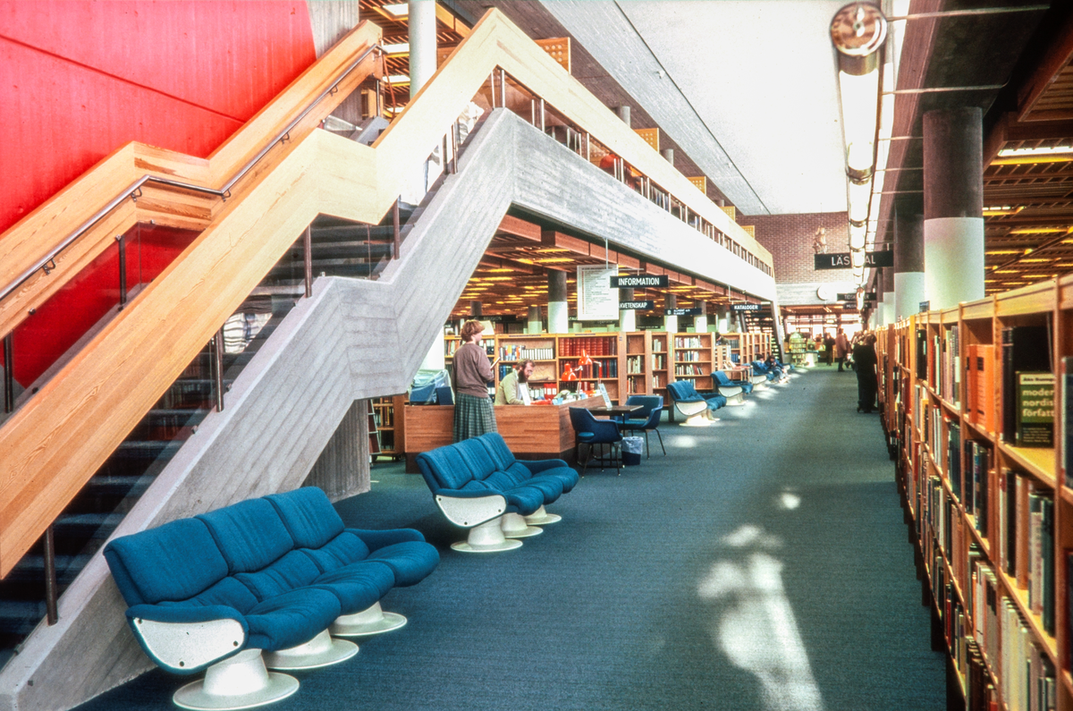 Bild från Linköpings stadsbibliotek på Hunnebergsgatan i Linköping, bilden är från 1980-talet. År 1973 flyttar Stifts- och landsbiblioteket in i denna byggnad, ritad av arkitekt Bo Cederlöf. Tidigare fanns biblioteket i en cirkelformad byggnad bakom Konsistoriehuset i Linköping. Båda dessa byggnader ligger i närhet till Linköpings domkyrka på var sin sida av Hunnebergsgatan. Den 20 september 1996 drabbades denna byggnad av en våldsam brand, som i det närmaste totalförstörde biblioteket. Huvuddelen av folkbiblioteksavdelningens öppna bokbestånd (ca 150 000 böcker) förstördes i branden. Idag (år 2024) ligger en ny biblioteksbyggnad på samma plats, dock med entrén åt andra hållet mot Östgötagatan. Kvar från denna byggnad finns idag bland annat en tegelvägg som man valt att behålla som minne av tiden före branden. Bilder från staden Linköping digitaliserade från diapositiv. Bilderna är från 1970-1990-talet.