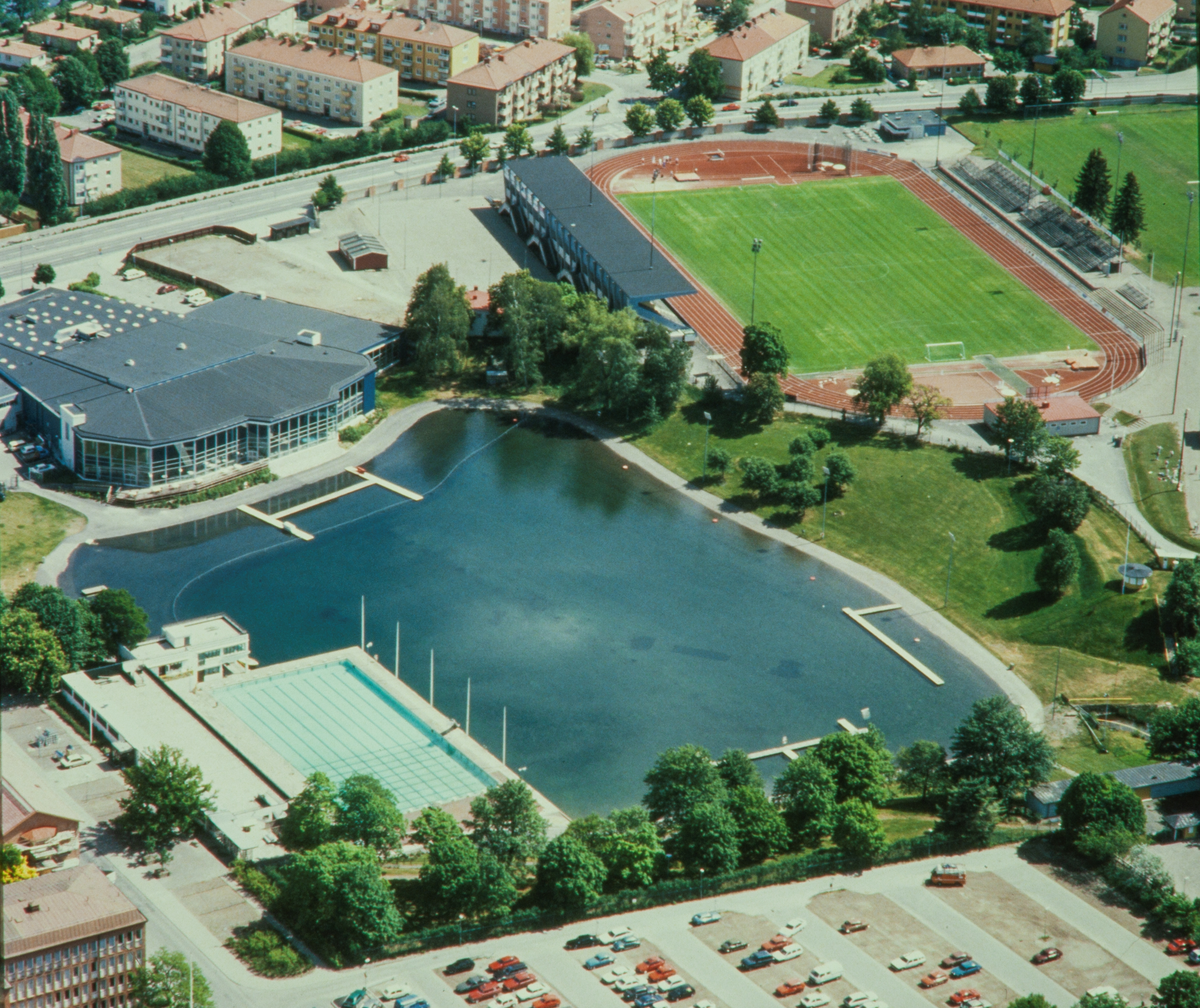 Flygbild över Linköpings simhall, Tinnerbäcksbadet och Folkungavallen. På gränsen mellan Tinnis och Folkungavallen ligger kiosken Gröna hatten som idag är flyttad till Gamla Linköping.

Om Linköpings simhall:

Linköpings simhall stod klar år 1965. Simhallens plats var bredvid Sporthallen på Hamngatan. Simhallen ritades av Hans Westman, samma person som ritat intilliggande Sporthallen. Kostnaden för bygget var nära 8 miljoner kronor.

Äventyrsbadet i Linköpings simhall var resultatet av en tillbyggnad år 1987.

Det tillkom även en 25-meters träningsbassäng för Lass

samt vågbassäng, vattenrutschbanor

och bubbelpooler. År 2001 byggdes utomhusvattenrutschbanan till.

Den 16/4 år 2023 stängdes Westmans simhall för att rivas. Den 22/4 öppnade Linköpings nya simhall- Tinnerbäcksbadet. Den nya simhallen byggdes bredvid den gamla simhallen på platsen där Linköpings idrottsplats, Folkungavallen en gång låg. Medley står för drift i samarbete med Linköpings kommun.

Bilder från staden Linköping digitaliserade från diapositiv. Bilderna är från 1970-1990-talet.