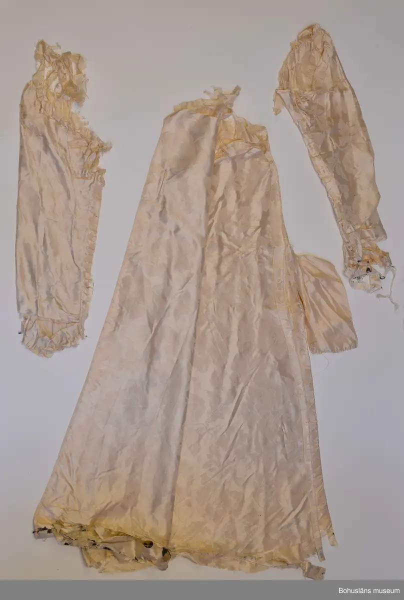 Kappa i svart sammet med vitt sidenfoder. Pellerinkrage och löst sittande skärp.