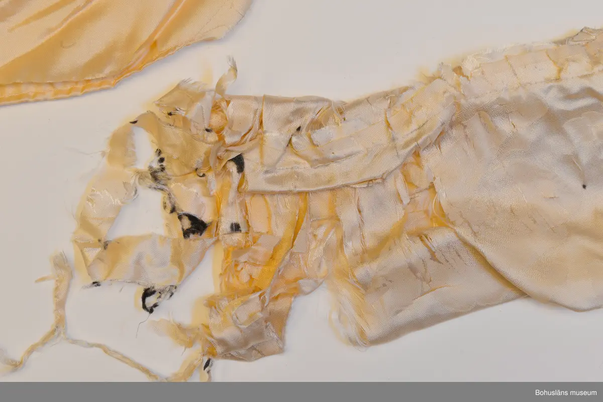 Kappa i svart sammet med vitt sidenfoder. Pellerinkrage och löst sittande skärp.