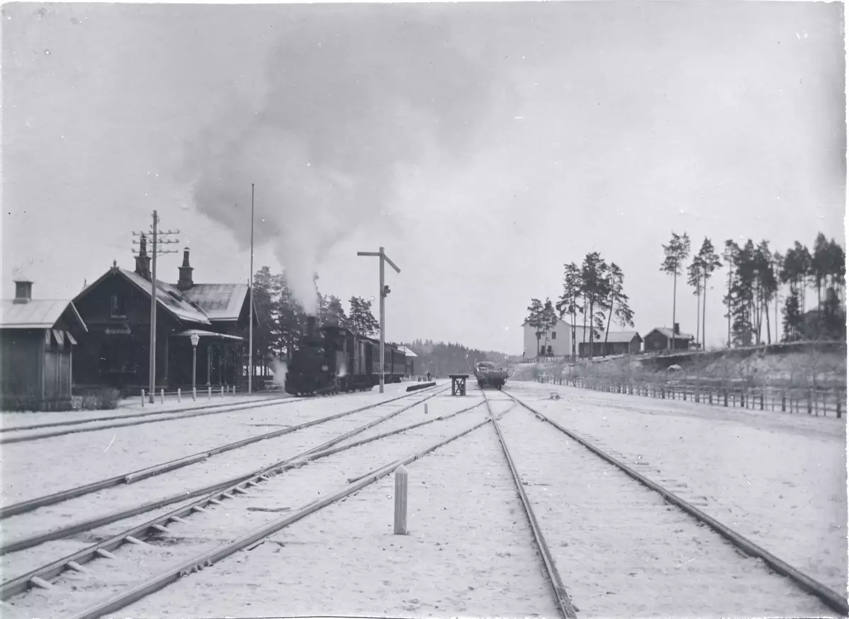 Nykvarns järnvägsstation i vinterskrud kring sekelskiftet 1900. Tåg på väg mot Eskilstuna