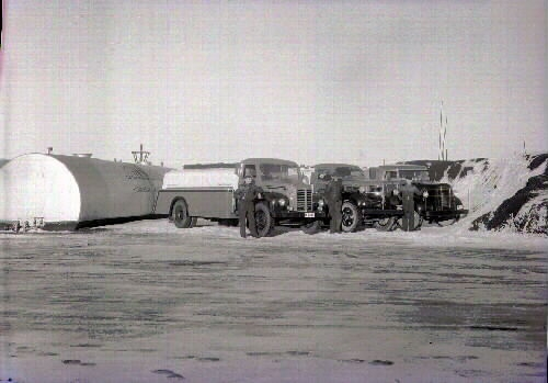 Tankbilar för eldningsolja etc hos Donald Jobson. Chaufförerna står uppställda vid sina lastbilar. Bild 1: Byggnaden t v är rodd- och kanotklubbens klubbstuga.