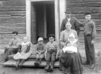 Familjen Gustafsson samlade för fotografering vid farstubron till hemmet Landamäre i Vist socken. Året är 1909 och vi som kan sia om familjens framtid kan berätta att parets barnaskara nu var fulltalig med halvårsgamla Sigvard Emanuel i knäet hos modern Emma Kristina. Husfadern, Anders Gustaf Gustafsson, med det svungfulla tillnamnet Sving, var uppvuxen i Landamäre och hade tagit över torpkontraktet efter faderns död 1886. Emma Kristina var född i Åtvid men inflyttad till Vist från Vårdnäs lagom till giftemålet 1894.