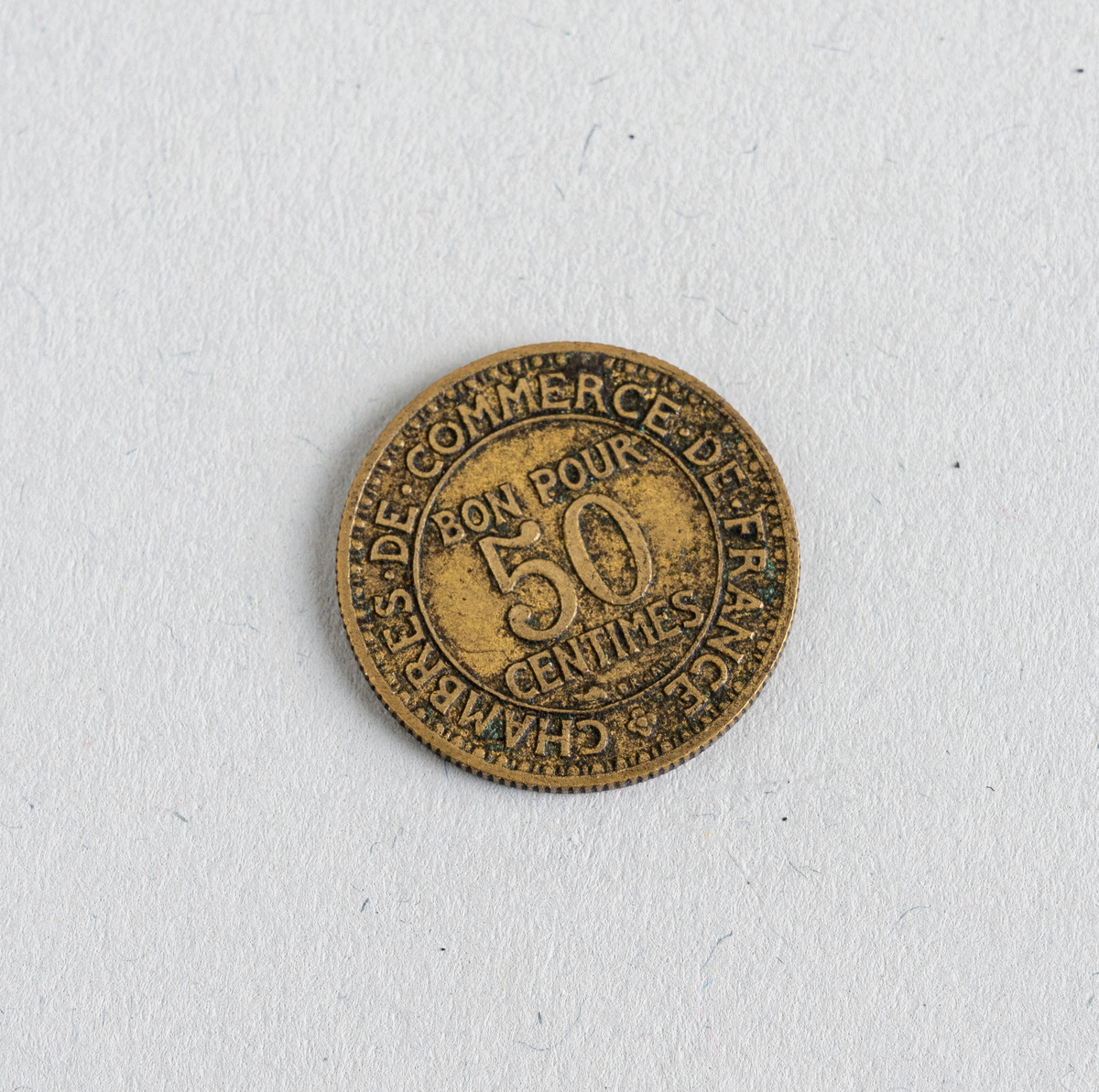 En fransk 50-centimes fra 1923. Mynten er laget av aluminium og kobber og fremstår som gullfarget. På den ene siden er det informasjon om valør og utsteder (Den Franske Sentralbank og mynten er verdt 50 centimes). På den andre siden er også tekst samt illustrasjon av handelsguden Merkur (gud for overflod og komersiell suksess). Der står også årstallet 1923. Mynten var en standard sirkulasjonsmynt.