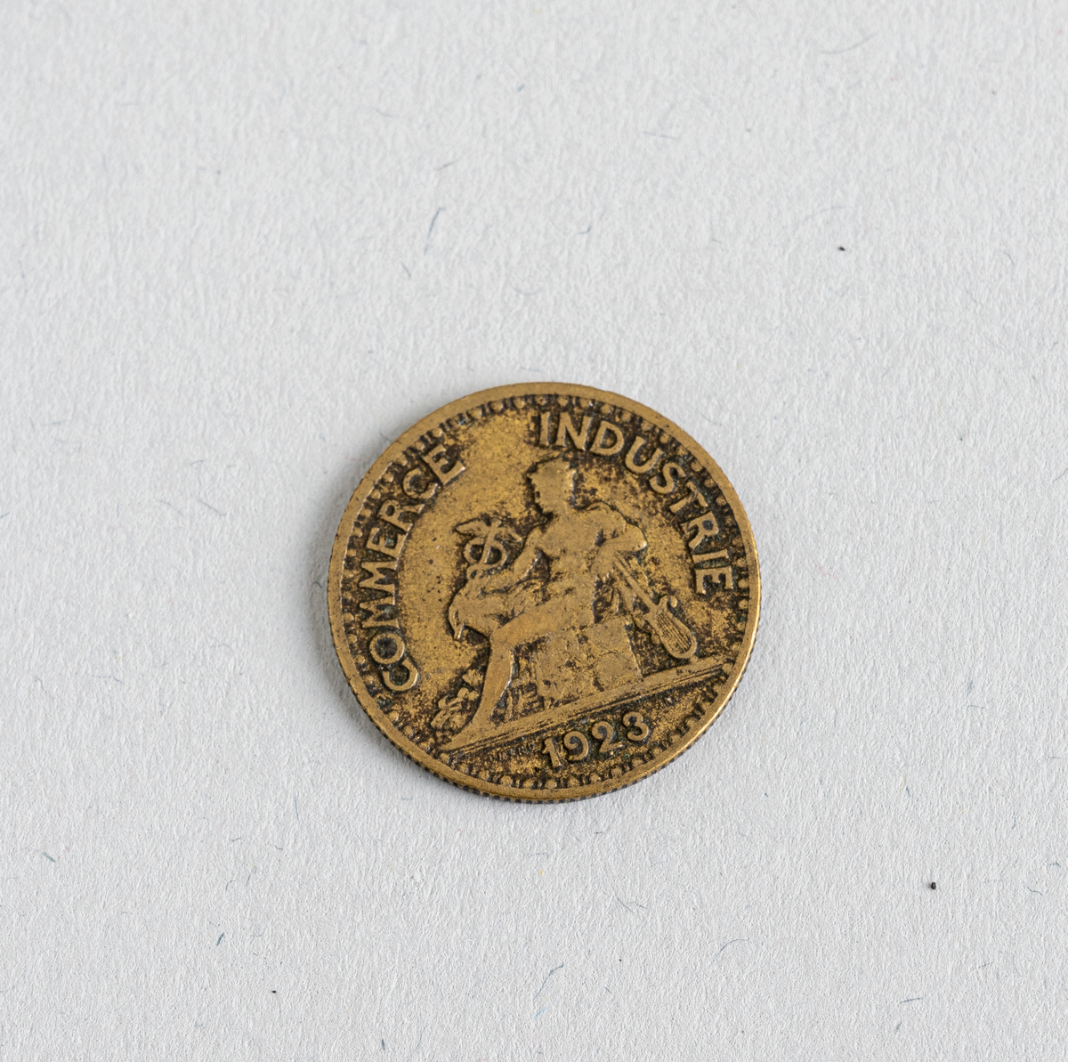En fransk 50-centimes fra 1923. Mynten er laget av aluminium og kobber og fremstår som gullfarget. På den ene siden er det informasjon om valør og utsteder (Den Franske Sentralbank og mynten er verdt 50 centimes). På den andre siden er også tekst samt illustrasjon av handelsguden Merkur (gud for overflod og komersiell suksess). Der står også årstallet 1923. Mynten var en standard sirkulasjonsmynt.