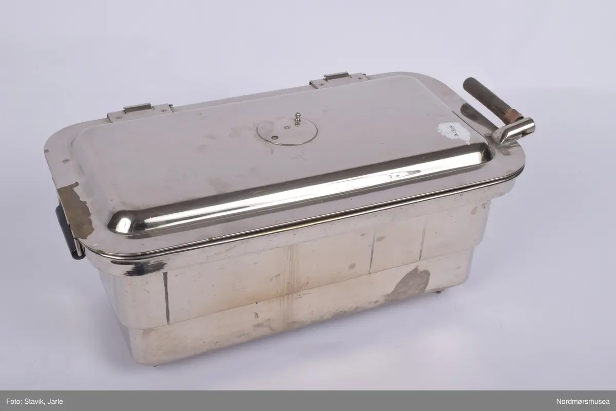 Elektrisk instrumentkoker i  rustfritt stål. Knopp på siden til å justere temperatur. En beholder innvendig med hanker og perforert bunn kan tas ut sammen med instrumentene når de er ferdig sterilisert.