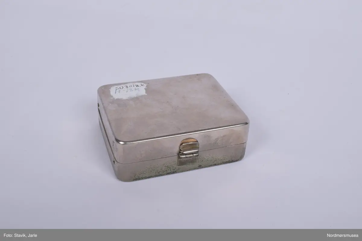 Legeveske i brukt skinn, åpning i toppen. Inneholder de fleste gjenstander man kan få bruk for ved sykebesøk. Dobbelt håndtak, lomme på utsiden kan lukkes med rein. Inni er hovedrom i bunnen med plastlommer med strikk øverst på en siden. Under denne to plastlommer med klaff. Et mindre skille av bunnen med skillevegg av gjenomsiktig plast. Inneholder numrene SU.3018a-3018s.
a) Etui for urinkatetere med fire katetre. Sylinder av gjennomsiktig plast med rød gummitopp i hver ende. 39 cm lang, 4 cm bred.
b) Sylindrisk metalletui i to deler for "smøreolje". Riller på siden fungerer som gjenger og dekorasjon. 78 cm langt, 4 cm diameter.
c) Todelt sylindrisk pappetui med reagensrør inni. 16,2 lang, røret 15,5 cm langt.
d) Termometer fra Villiers, merket ATOMIC. Liten glasshempe i toppen. 17 cm langt.
e) Tomt etui i messing med røde plastender. Irret.
f) Tomt etui i brunt skinn for blodtrykksapparat. Glidelås langs begges sider og topp. 17x12 cm.
g) Etui i eggehvit plast. Todelt med hengsling, inneholder staseslange produsert av Premeta Stauer. Brukes ved blodprøvetagning for å stramme rundt armen for å få fram blodårene.
m) Saks med krumme blader. 13 cm lang.
n) Skaplell med utfellbart blad. En skyvelås brukes for å hindre bladet i å folde seg sammen. Produsert av A. Rudds eftf. 14,5 cm lang utslått.
o) Anatomisk pinsett prdusert av Stille - Sverige. 13 cm langt.
p) To artieriepinsetter. Sakslignende pinsetter for å klipe igjen blodårer.
r) 4 pakker med steril suturtråd prod. av Davis & Beck Division American cyanid company. 1 pakke gasbind 4cmx5cm, 1 pk steril bomullsbandasje prod. av Beng & tegner & Co 25gr, 1 pk steril gasbind 1/4m, 1 stk trekantforkle 2,70.
s) 2 tungespatler i plast, 14,5 cm lang.