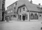 Linköping 1931, mitt i svåra tider för byggbranschen med sänkta löner och uppsagda avtal. Här och var byggdes det ändå, som här på tomten till den anrika restaurangen Druvans tidigare läge. I sammanhanget breddades även gatuavsnittet. Det färdiga affärs- och bostadshuset fick adressen Bokhållaregatan 1. Något senare revs det gamla hörnhuset och byggnaden under produktion förlängdes till Nygatan.