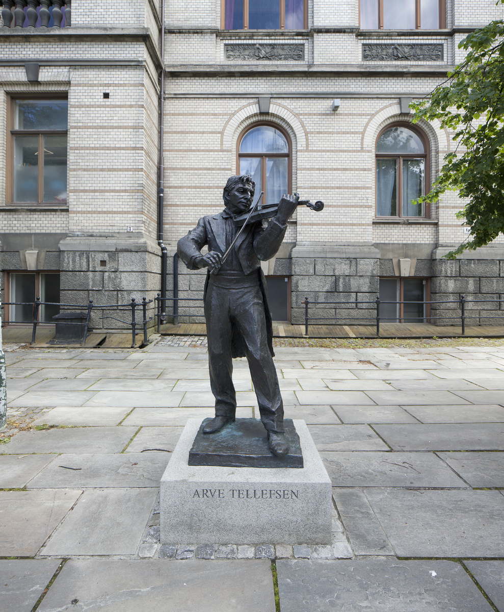 Helfigur på sokkel av fiolinist Arve Tellefsen som spiller fiolin. 

Arve Tellefsen er født i Trondheim 14.desember 1936. Han debuterte som konsertfiolinist i 1959 og har  spilt inn over 30 cder. Tellefsen stiftet Oslo Kammermusikkfestival i 1989. Han er utnevnt som kommandør av St.Olavs Orden og æresborger av Trondheim.